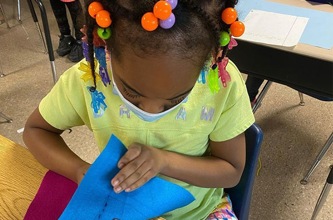 Student sewing a softie to gift to a person in her community