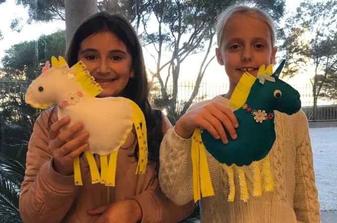 girls holding a felt unicorn softie