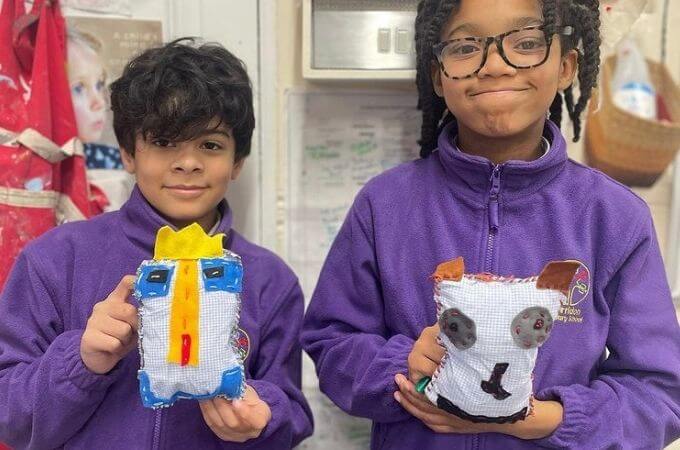 children holding a stuffie they have sewn