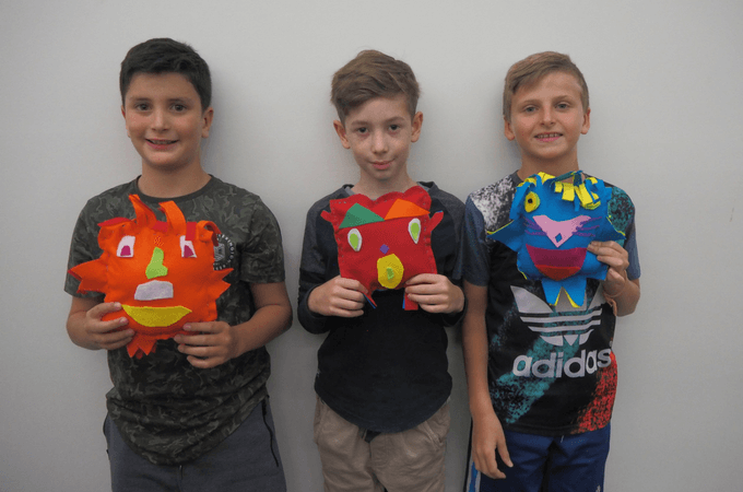 three boys holding softies they've just sewn